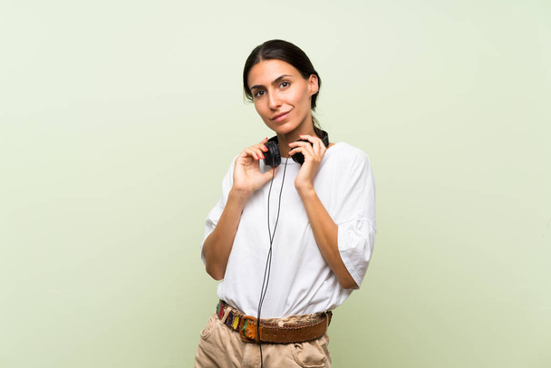 Fiatal nő több mint elszigetelt zöld háttér hallgat zenét fejhallgató - Fotó, kép