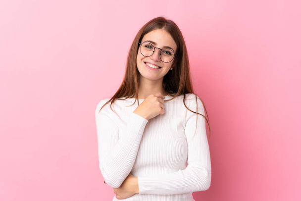 Junge Frau auf isoliertem rosa Hintergrund mit Brille und lächelnd - Foto, Bild