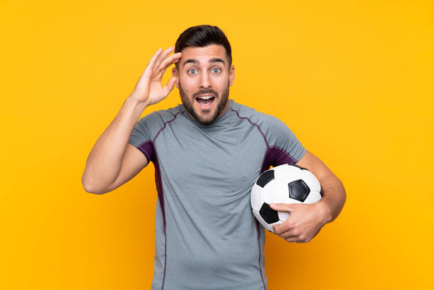 Ποδοσφαιριστής άνθρωπος πάνω από απομονωμένη φόντο με έκπληξη και σοκαρισμένη έκφραση προσώπου - Φωτογραφία, εικόνα