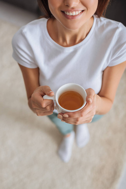 vista ritagliata di allegra ragazza in possesso di tazza con tè
  - Foto, immagini