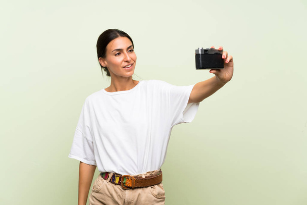 junge Frau vor isoliertem grünen Hintergrund macht ein Selfie - Foto, Bild