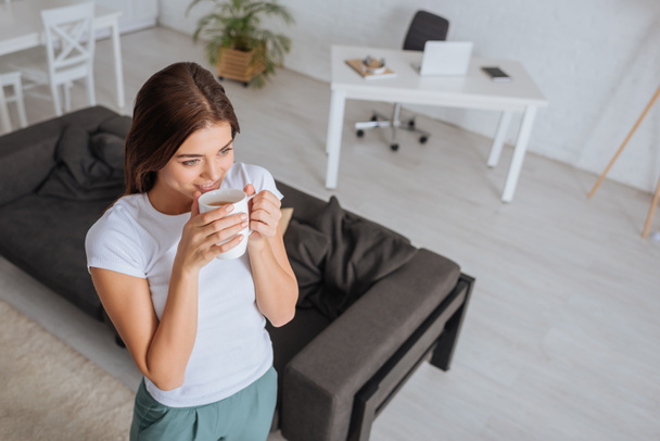 shora pohled na atraktivní žena pití čaje v obývacím pokoji  - Fotografie, Obrázek