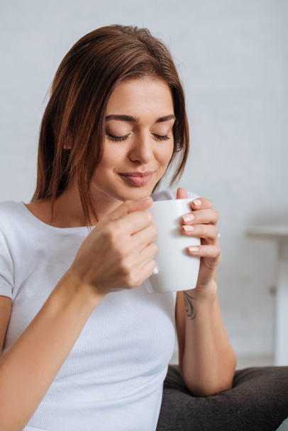 young woman with closed eyes holding cup of tea  - Foto, afbeelding