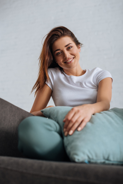 selective focus of cheerful girl looking at camera while chilling on sofa  - Photo, Image