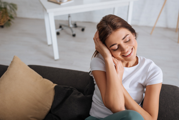 joven mujer sonriente con los ojos cerrados enfriamiento en la sala de estar
  - Foto, imagen