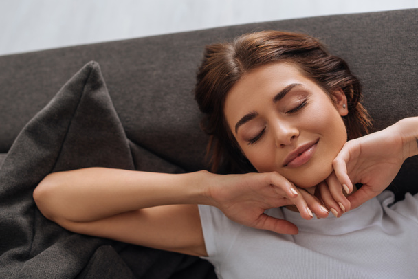 top view of beautiful woman dreaming while resting on sofa in living room  - Photo, Image