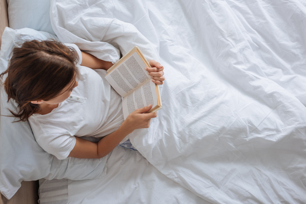 Mädchen lesen Buch, während sie im Bett chillen  - Foto, Bild