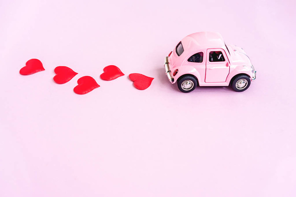 Pink retro toy car delivering craft heart for Valentines day - Photo, Image