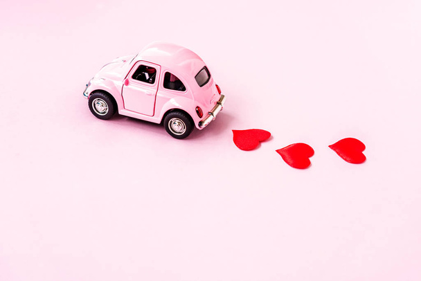 Розовый ретро игрушечный автомобиль, доставляющий ремесленное сердце на День Святого Валентина
 - Фото, изображение