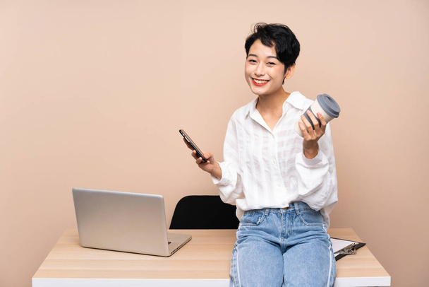 Young business Asian girl in her workplace holding coffee to tak - Photo, Image