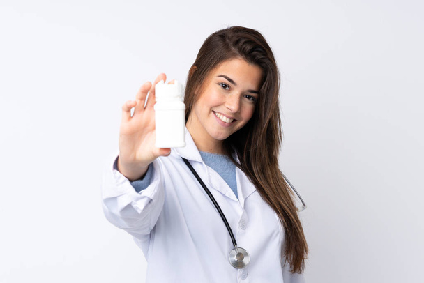 Дівчина-підліток над ізольованим білим тлом в одязі лікаря і тримає таблетки
 - Фото, зображення