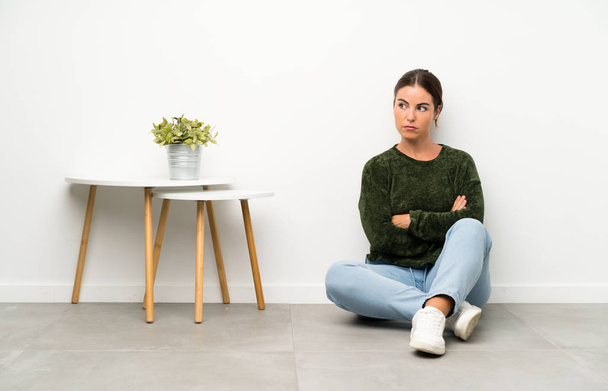 Młoda kobieta siedząca na podłodze myśląca o pomyśle - Zdjęcie, obraz