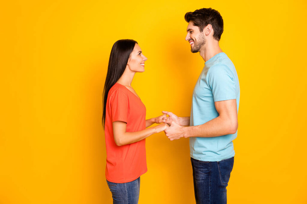 Profile photo of lovely two people couple guy and lady hold arms look eyes romance love declaration wear casual blue orange t-shirts jeans isolated over yellow color background - Fotografie, Obrázek