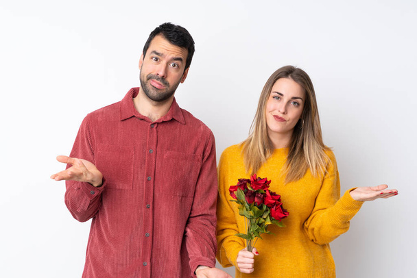 Para w Walentynki trzymając kwiaty na odosobnionym tle nieszczęśliwy i sfrustrowany czymś, ponieważ nie zrozumieć coś - Zdjęcie, obraz