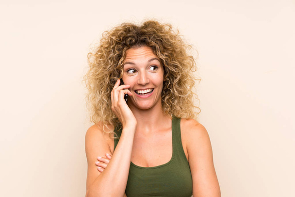 Nuori blondi nainen, jolla on kiharat hiukset matkapuhelimella
 - Valokuva, kuva