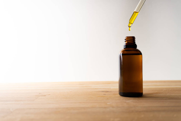aceite de CBD o cualquier otro aceite que cae en una pequeña botella de pie sobre una tabla de madera fondo blanco
 - Foto, Imagen