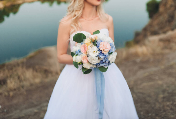 Wedding bouquet in bride's hands on nature background. - Zdjęcie, obraz