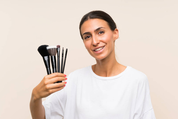 Young woman holding a lot of makeup brush smiling a lot - Zdjęcie, obraz
