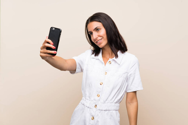 Jonge vrouw over geïsoleerde achtergrond maken van een selfie - Foto, afbeelding