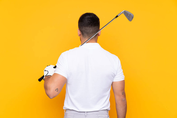 Man over isolated yellow background playing golf - Valokuva, kuva