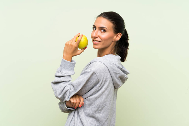 Fiatal sport nő egy almát egy elszigetelt zöld háttér  - Fotó, kép