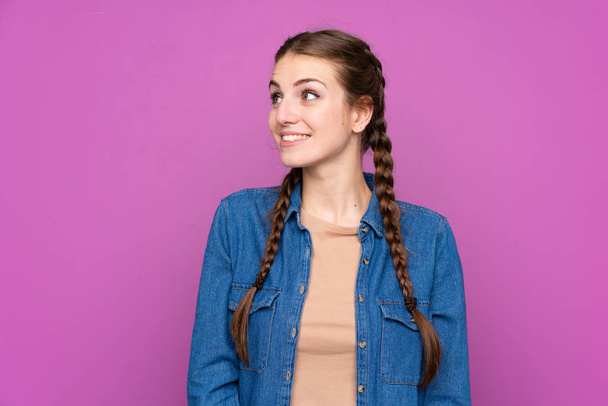 Νεαρή γυναίκα πάνω από απομονωμένο μωβ φόντο γέλιο και κοιτάζοντας πάνω - Φωτογραφία, εικόνα
