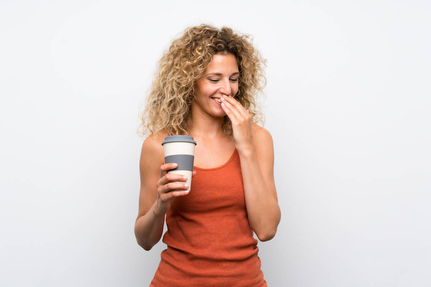 Sarışın, kıvırcık saçlı, elinde kahveyle gezen genç bir kadın. - Fotoğraf, Görsel