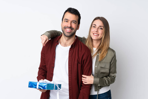 Couple in Valentine Day holding a gift over isolated background hugging - Photo, Image