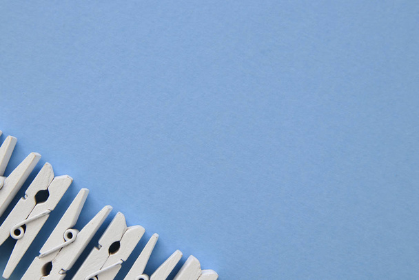 White clothespins in a row on blue background. Flat lay, negativ - Photo, Image