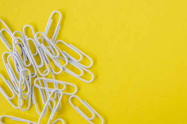 White paperclips on a bright yellow background - Fotografie, Obrázek