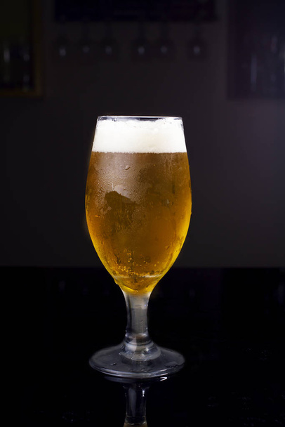 Ποτήρι γεμάτο μπύρα, με chopp pilsen σε σκούρο φόντο σε μια παμπ - Φωτογραφία, εικόνα