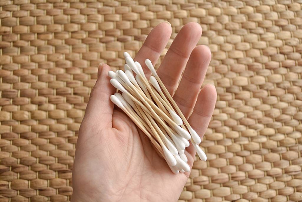 Bamboo ear sticks in woman hand, natural eco cotton swabs, zero waste, sustainable lifestyle. - 写真・画像