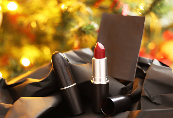 bodegón de lápiz labial rojo frente al árbol de Navidad - publicidad cosmética mujer
 - Foto, imagen