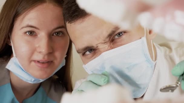 Odontólogos profesionales enmascarados con herramientas dentales en la mano examinan la cavidad oral
 - Metraje, vídeo