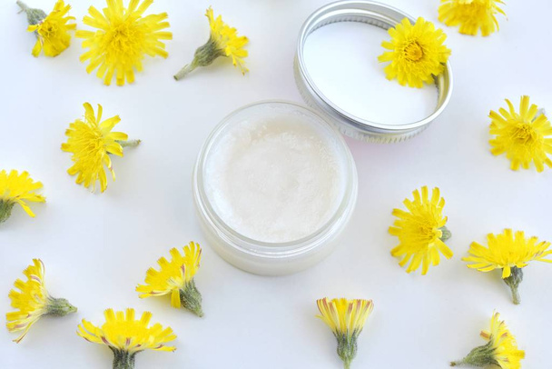 Natural, organic, homemade lip balm in small container, handmade cosmetic, flat lay with yellow flowers. - Photo, Image