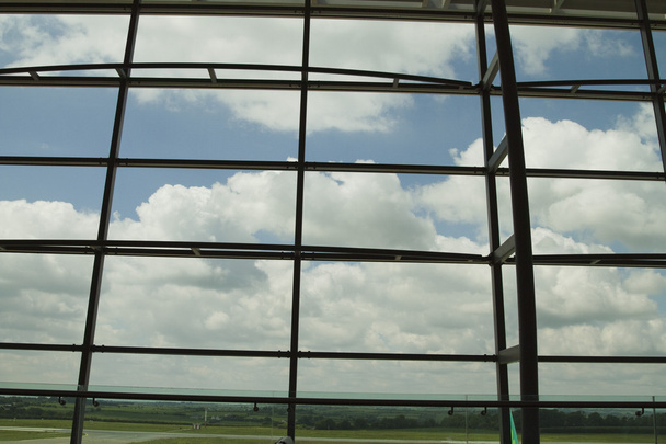 Pilvet nähtynä lentokentän aulatilan ikkunasta
 - Valokuva, kuva