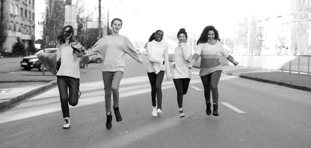 Çok ırklı bir arkadaş grubu şehir sokaklarında koşuyor ve eğleniyor.. - Fotoğraf, Görsel
