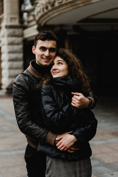 Attractive young couple walking near castle. Wife and husband kissing and holding hands on background of ancient building. Two smiling lovers. Family and love concept - Fotó, kép