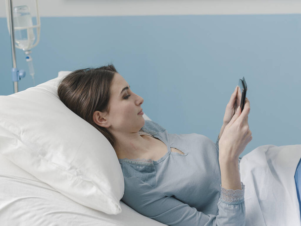 Young patient lying in bed and connecting with a digital tablet - Foto, immagini