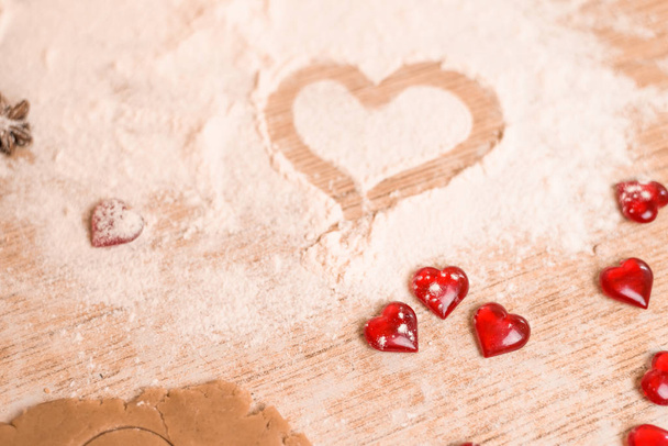 The concept of baking for Valentine's Day with torches in the shape of a heart . the heart is drawn on the flour in the process of making cookies - Foto, Bild