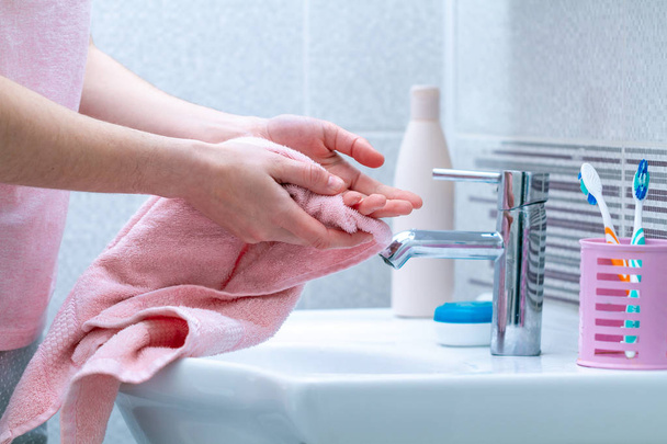 Person wipe hands dry with towel after washing in bathroom at home. Hygiene and hand care.  - Valokuva, kuva