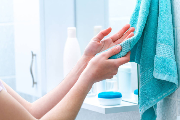 Woman wipe hands dry with towel after washing in bathroom at home. Hygiene and hand care.  - Φωτογραφία, εικόνα