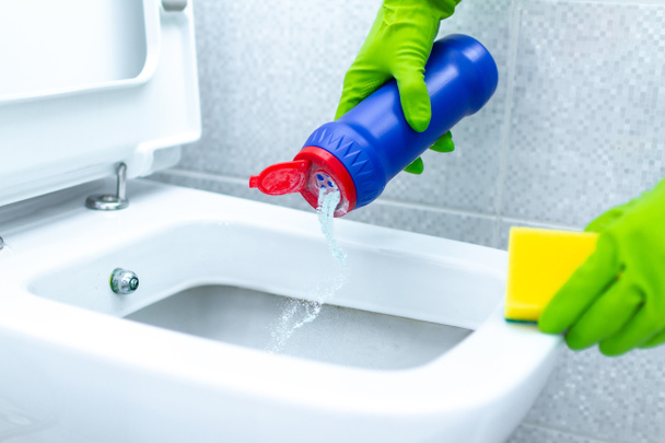 Gospodyni domowa w gumowych rękawiczkach czyszcząca i dezynfekująca toaletę przy użyciu środków czyszczących i gąbki. Prace domowe - Zdjęcie, obraz