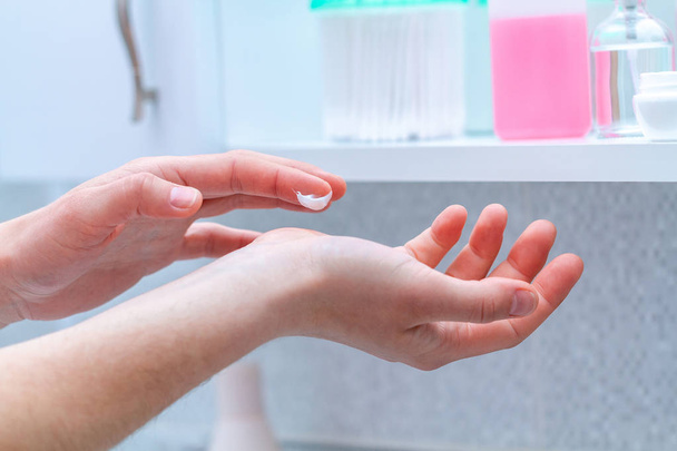 Applicando crema per le mani idratante e nutriente per la pelle secca in bagno a casa. Cura della pelle, nutrizione
  - Foto, immagini