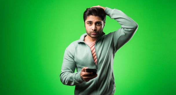 Komea Intian tai Aasian masentunut mies seisoo eristetty yli vihreä tausta näyttää stressaantunut ja hermostunut ottaa ahdistus ongelma. valikoiva kohdentaminen - Valokuva, kuva