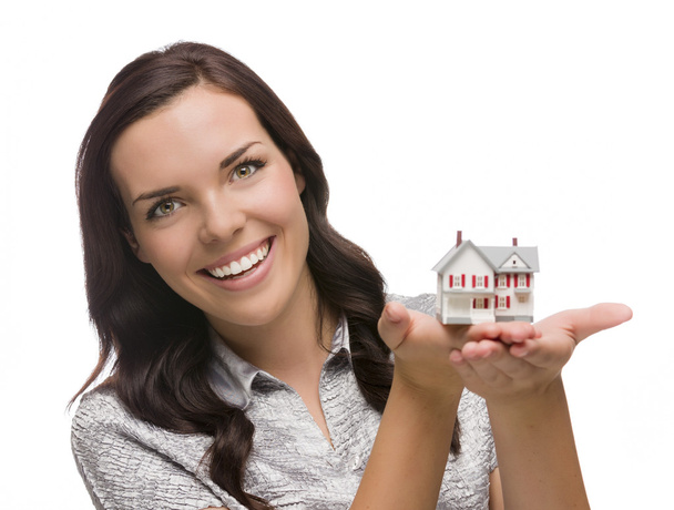 Lachende vrouw van gemengd ras holding klein huis geïsoleerd op wit - Foto, afbeelding