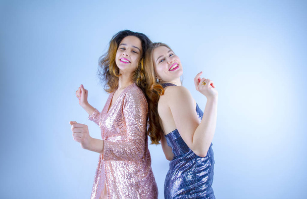 Two attractive and funny girlfriends wearing in shiny dresses, princes having fun and making face. Women dancing, posing. Fun Party concept.Copy space - Photo, Image