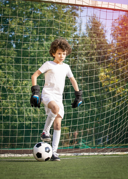 Summer soccer tournament for young kids. football club. emotions and joy of the game. Young goalie. Kids - soccer champion. Boy goalkeeper in football sportswear on stadium with ball. Sport concept. - Φωτογραφία, εικόνα