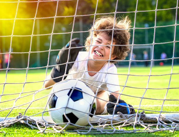 Summer soccer tournament for young kids. football club. emotions and joy of the game. Young goalie. Kids - soccer champion. Boy goalkeeper in football sportswear on stadium with ball. Sport concept. - Фото, изображение