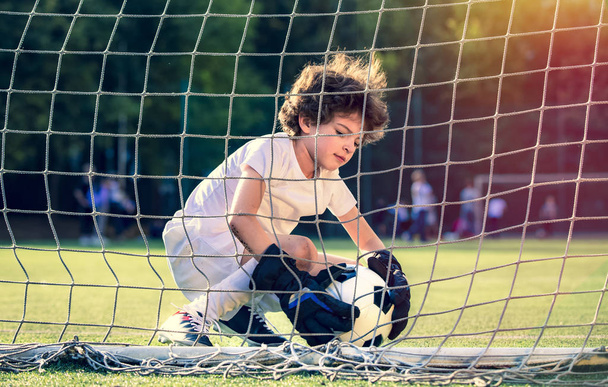 Summer soccer tournament for young kids. football club. emotions and joy of the game. Young goalie. Kids - soccer champion. Boy goalkeeper in football sportswear on stadium with ball. Sport concept. - Photo, Image